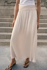 Falda midi de tiro alto con detalle de frunces en la cintura y tejido satinado con efecto arrugado. Presenta un corte fluido y cierre lateral con cremallera oculta.