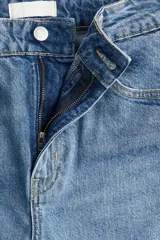 Jean tobillero de tiro alto, color azul medio lavado, con cinco bolsillos y pierna recta ligeramente ajustada.