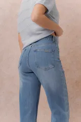 Jean de denim celeste con lavado claro, corte recto y tiro medio-alto, con diseño de cinco bolsillos y cierre frontal con botón y cremallera.