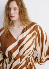 Vestido midi con estampado animal print tipo cebra en tonos marrón y blanco, de corte recto, con escote en V, mangas tres cuartos y tajo delantero en la falda. Incluye un cinturón fino ajustable.