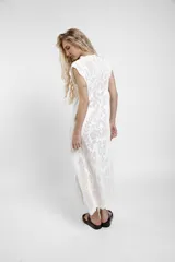 Vestido largo de crochet color crudo, con mangas cortas con volados y aberturas laterales, confeccionado en tejido calado de algodón con diseño ornamentado.