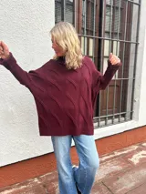 Polera de tejido de punto con diseño de ochos, color bordó, de corte oversize y cuello alto, con puños y ruedo acanalados.