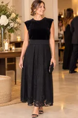 Vestido midi negro con cuerpo de terciopelo y canesú con bordado de cuentas en el cuello, falda amplia de encaje y seda trabajada.