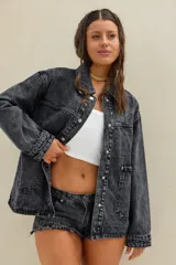 Campera de jean oversize en color negro con efecto acid wash, de mangas largas, cuello camisero, bolsillos frontales con solapa y cierre mediante botones metálicos.