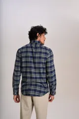 Camisa de manga larga confeccionada en tejido de franela con estampado de cuadros en tonos azul marino y verde. Presenta cuello abotonado, cierre frontal con botones y un bolsillo en el pecho con el logo bordado de la marca.