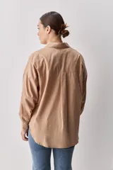 Camisa celeste de corte oversize, con mangas largas, cuello camisero y cierre frontal de botones.