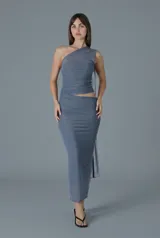 Vestido largo gris de un solo hombro con diseño asimétrico, drapeado en el cuerpo y detalle de aberturas (cut-outs).