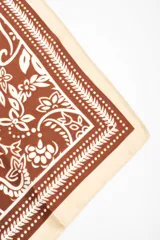 Bandana de diseño cuadrado en tono marrón y blanco con estampado de arabescos y flores, con bordes en color marfil.
