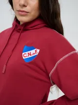 Canguro deportivo Umbro del Club Nacional de Football, color bordó, con capucha ajustable con cordón, bolsillo tipo canguro y costuras visibles en contraste. Presenta el logo de Umbro y el escudo del club bordados en el frente.