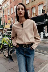 Campera bomber color beige, de cuello redondo y manga larga. Tiene bolsillos delanteros y bajo acabado en elástico. Cierre frontal con cremallera.