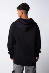 Buzo canguro oversize de tela friza, color negro, con capucha, cordones ajustables con logo y bolsillo frontal tipo canguro.