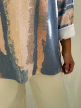 Sweater de tejido de punto con diseño abstracto en tonos azul, beige y rosado, de corte holgado y mangas largas con puños vueltos.