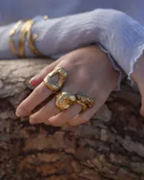 Anillo plateado con forma orgánica irregular y un agujero en el centro.