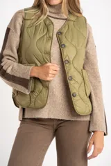 Chaleco acolchado color verde oliva, con diseño capitoneado de ondas, cierre frontal con botones y bolsillos laterales.