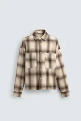 Camisa de algodón con cuello solapa, manga larga y dos bolsillos plastrón en el delantero. Presenta un patrón de cuadros en tonos beige y marrón oscuro.