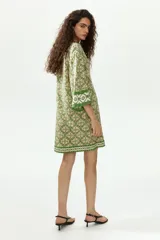 Vestido túnica corto de viscosa con estampado geométrico en tonos verdes y crudo, escote en V pronunciado tanto en el frente como en la espalda, mangas tres cuartos y diseño oversized.