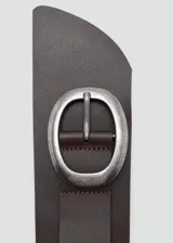 Cinto ancho de cuero vacuno en color marrón oscuro, estilo fajín, con hebilla ovalada grande de metal plateado envejecido.