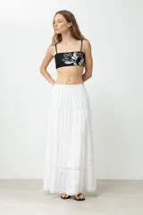 Top de bikini negro con tirantes finos y bordado de flores blancas.