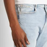 Jean slim de hombre color azul claro, con cinco bolsillos y cierre de botón y cremallera.