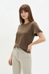 Remera blanca de algodón, de corte ajustado, con cuello redondo y mangas cortas terminadas con volados delicados.
