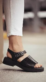 Sandalia de cuero color negro con combinación de texturas, base de goma liviana, diseño chunky, tiras anchas en el empeine y tira con hebilla ajustable en el tobillo.