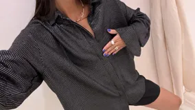 Camisa oversize color verde militar con finas rayas verticales de lurex, cuello camisero y mangas largas con puños anchos.