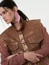 Chaleco denim rosa con efecto metalizado plateado, sin mangas y con cierre de botones.