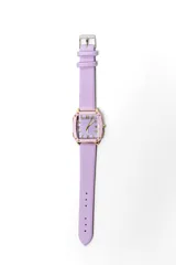 Reloj de pulsera con caja cuadrada dorada, bisel en tono rosado y esfera lila con números romanos y detalles de cristales. Cuenta con una correa de cuero sintético en color lila.
