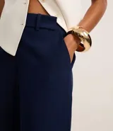 Pantalón de vestir azul marino, de corte amplio, con cintura alta, cinturón incorporado y cierre delantero.