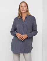 Camisa de corte largo y holgado, con estampado de rayas verticales en azul marino y blanco. Presenta cuello con solapa, cierre frontal con botones, bolsillo en el pecho y mangas largas con puños abotonados.