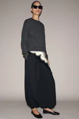 Pantalón de tiro medio, color negro con rayas diplomáticas finas blancas. Cintura elástica ajustable con cordones y bajo abullonado con elástico.