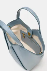 Bolso mini shopper de cuero sintético en color marrón, con diseño estructurado y costuras decorativas contrastantes. Cuenta con doble asa de mano y cierre magnético.