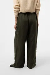 Pantalon de lino verde militar, de calce relajado y pierna amplia, con cintura elastizada, boton delantero y pinzas en el frente.