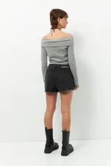 Short pollera de jean prelavado color negro, con lazo en uno de sus laterales y detalle de flecos en las terminaciones.