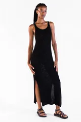 Vestido largo negro de punto con hilo lurex brillante, sin mangas, con escote redondo y aberturas laterales.
