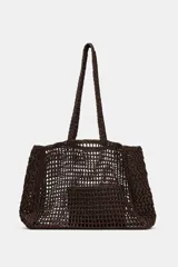 Bolso tipo maxi shopper de rafia tejida en color marrón oscuro, con asas de hombro trenzadas. Incluye un compartimento interior extraíble con cierre de cremallera.