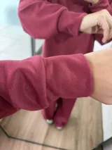 Conjunto de dos piezas color bordó, compuesto por un buzo de cuello redondo con mangas largas y un pantalón de corte holgado con cintura elástica.