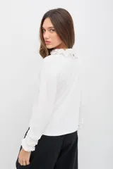 Polera de manga larga color azul jaspeado, con cuello alto y puños decorados con volados. Presenta un calce cómodo y relajado.