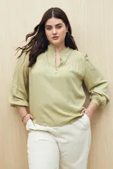 Camisa verde claro de viscosa suave, con cuello mao y botonadura parcial al frente. El detalle de frunces en los hombros y los puños abotonados le suman delicadeza y estilo.