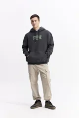 Canguro con capucha y cordones ajustables, confeccionado en algodón con detalle de estampado frontal en tonos verdes. Presenta un bolsillo tipo canguro delantero, puños y ruedo acanalados.