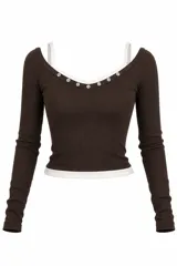 Remera de punto ajustada al cuerpo, color negro con detalles de ribetes blancos en el escote cuadrado y en el ruedo. Presenta botones decorativos a lo largo del escote y mangas largas.