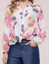 Camisa de gasa blanca con estampado floral multicolor, cuello con solapa, mangas largas y cierre frontal con botones. Cuenta con terminación delantera anudada y espalda más larga.