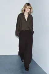 Blusa de la colección Zara Woman, confeccionada en hilatura de viscosa con estampado de cuadro vichy en tonos marrón y negro. Presenta cuello solapa, manga larga con puño y bajo ajustable con cordones. Cierre frontal con botones.