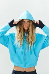 Sudadera con capucha ajustable con cordones, cierre frontal de cremallera, mangas largas, bolsillos tipo canguro y efecto lavado en color celeste.