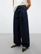 Pantalón de denim azul oscuro, de pierna ancha, con cierre de botón y cremallera, bolsillos laterales oblicuos, bolsillos parche traseros, pespuntes a contraste, cinturilla interior de sastrería, ceñidor y goma para dos posiciones, y bajo con goma y ceñidor.