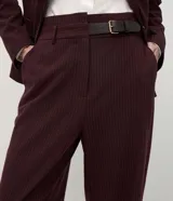 Pantalón de sastrería corte recto, color bordó con estampado de rayas finas verticales. Confeccionado en crepé, cuenta con cintura estructurada con trabillas, bolsillos funcionales y un medio cinturón incorporado de material sintético con hebilla metálica.