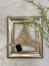 Tanga corte media colaless de encaje color tostado, con entrepierna de algodón y tiras regulables.