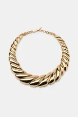 Collar tipo gargantilla compuesto por piezas metálicas doradas de diseño curvo y acabado brillante, unidas entre sí con una cadena de eslabones en la parte posterior y cierre de mosquetón.