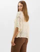 Cardigan abierto estilo kimono, color crudo, con mangas amplias al codo. Presenta una base con textura y motivos florales bordados a tono, con paneles de encaje calado estilo macramé en el frente, puños y ruedo.