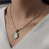 Gargantilla con cadena de eslabones plateados y dije circular con borde dorado y centro de nácar calado.